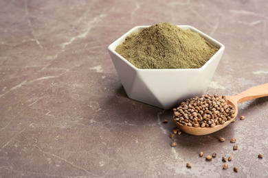 Photo of Hemp protein powder in bowl and spoon with seeds on table. Space for text