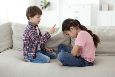 Upset brother and sister having argument on sofa at home