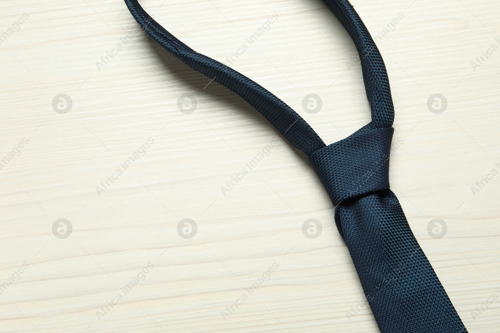 Photo of One blue necktie on white wooden table, top view. Space for text