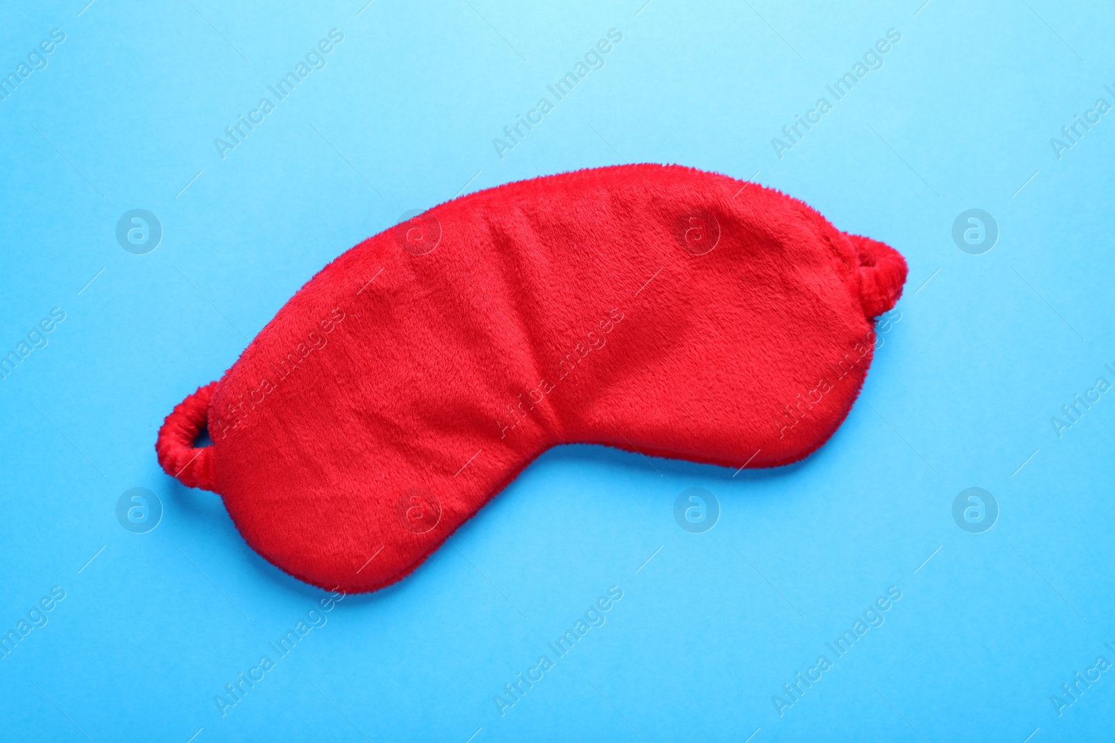 Photo of Soft sleep mask on light blue background, top view