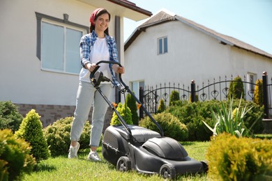 Photo of Woman cutting green grass with lawn mower in garden