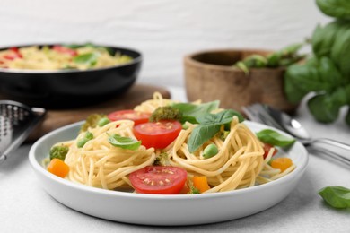 Photo of Delicious pasta primavera, ingredients and cutlery on light gray table, closeup