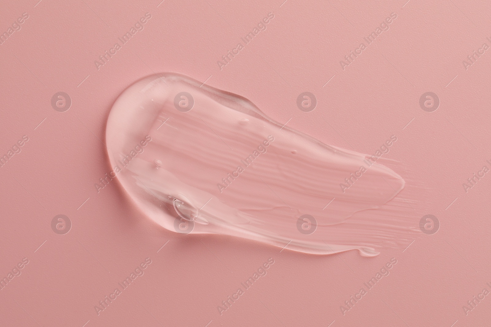 Photo of Smear of clear cosmetic gel on pink background, top view