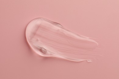 Smear of clear cosmetic gel on pink background, top view