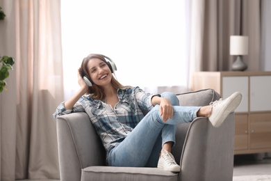 Young woman with headphones resting in armchair at home