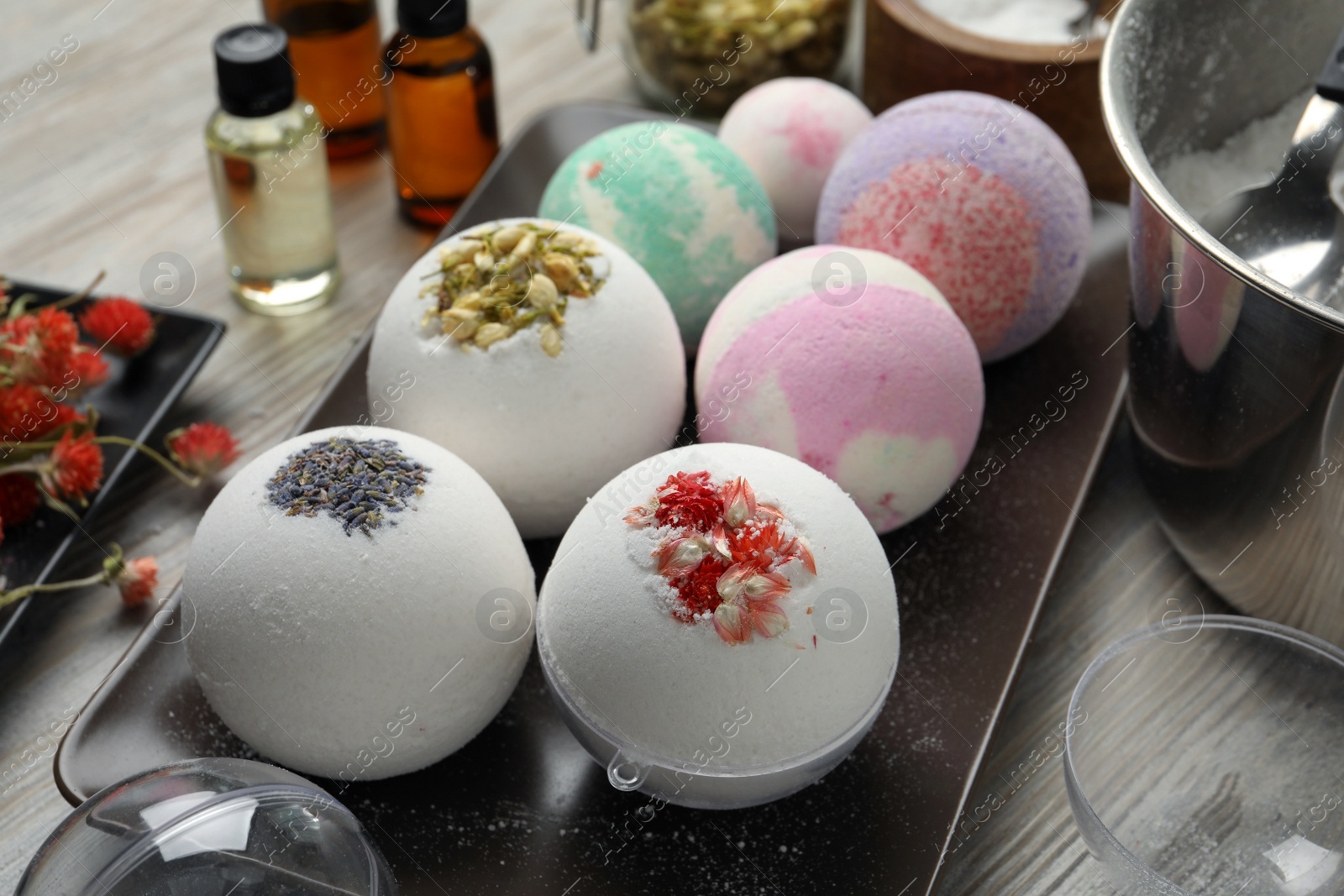 Photo of Plate with different bath bombs on wooden table, closeup