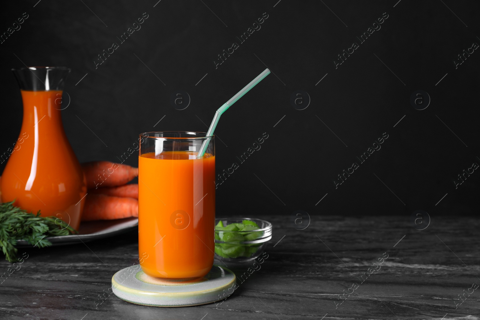 Photo of Tasty carrot juice on black marble table, space for text