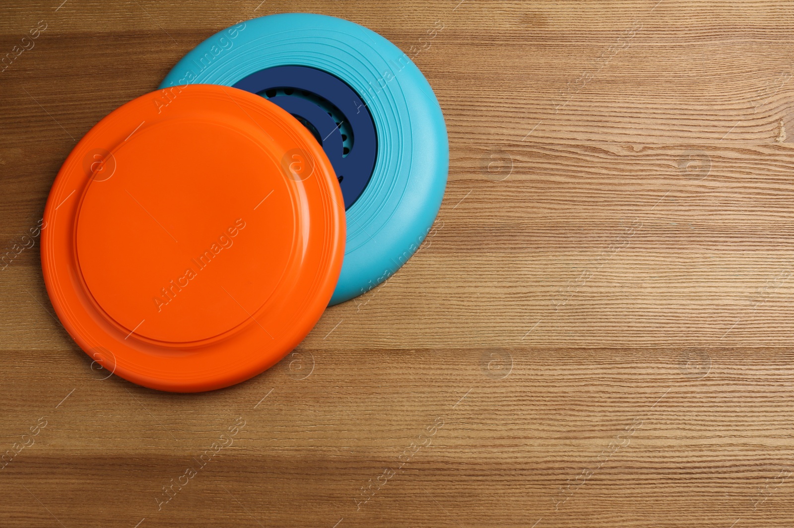 Photo of Plastic frisbee disks on wooden background, flat lay. Space for text