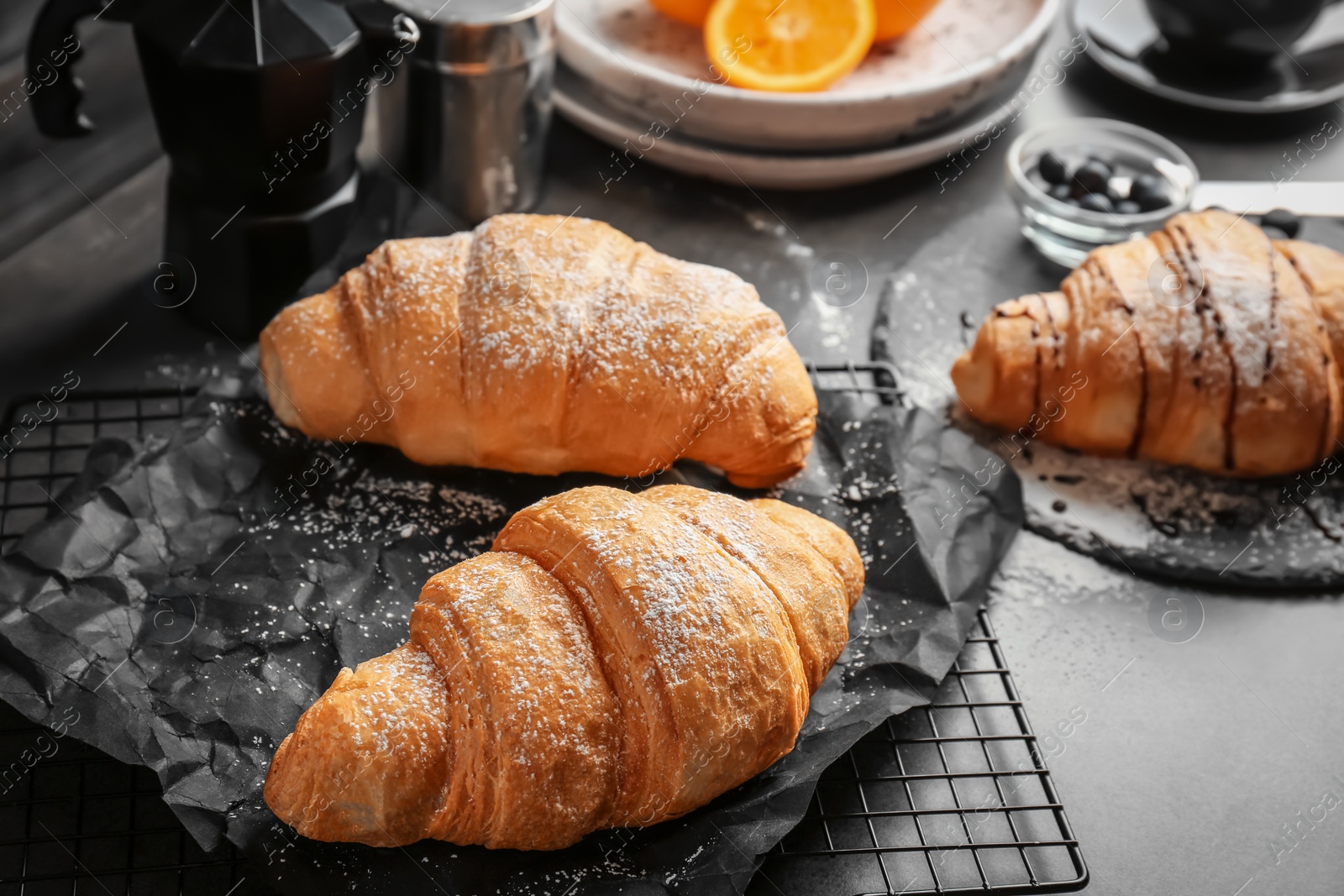 Photo of Tasty croissants with sugar powder on cooling rack