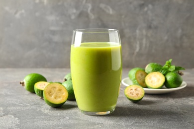 Photo of Fresh feijoa smoothie and fresh fruits on grey table, closeup