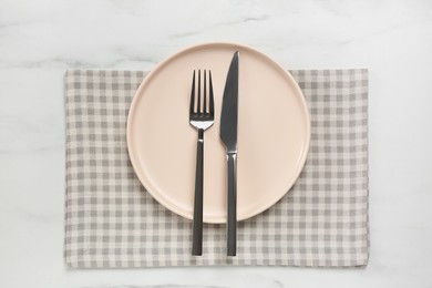 Photo of Clean plate with shiny silver cutlery on white marble table, flat lay