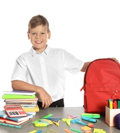Schoolboy at table with stationery against white background