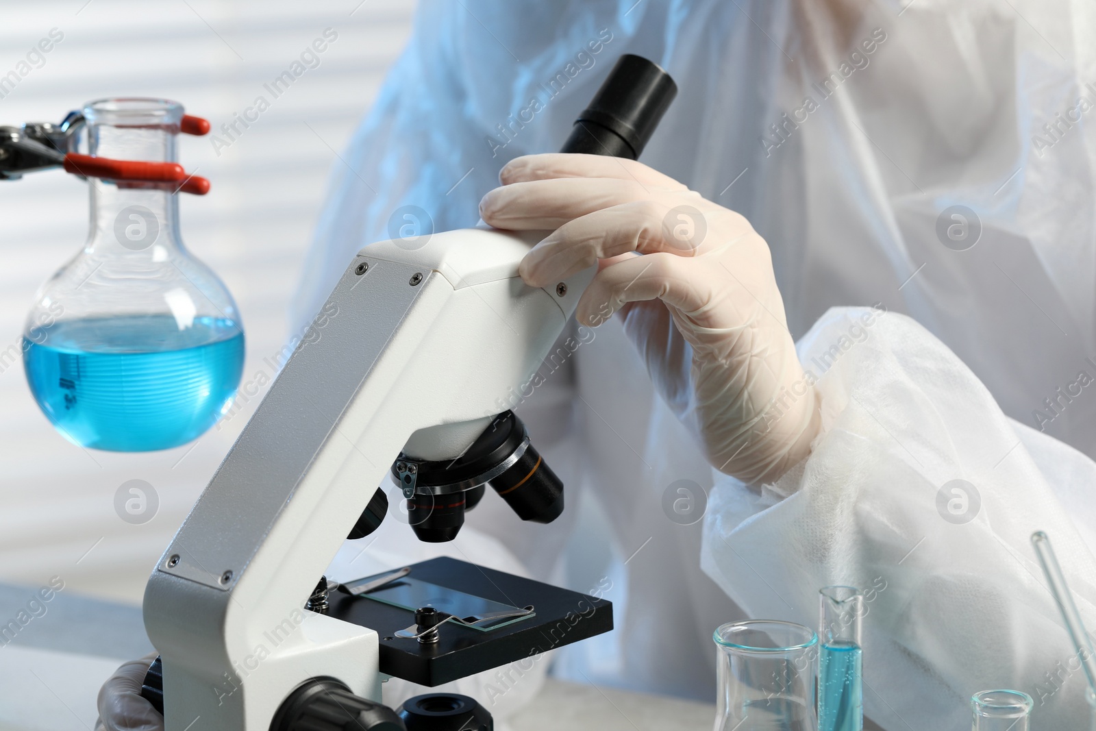 Photo of Scientist working with microscope in laboratory, closeup