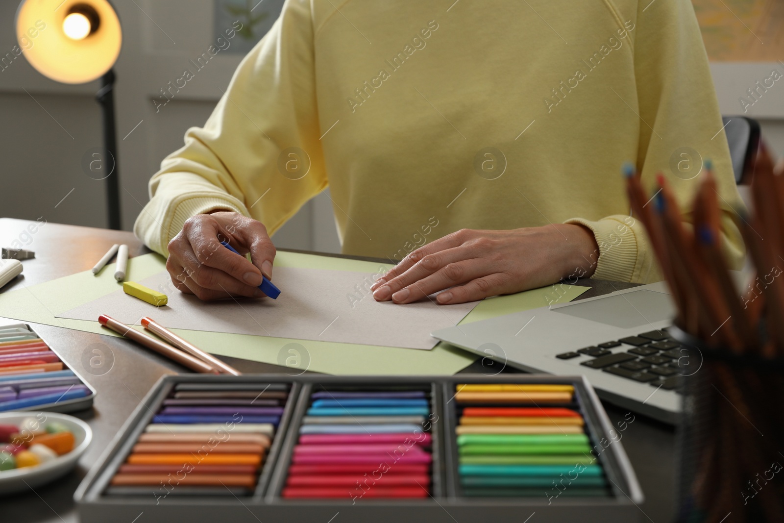 Photo of Artist drawing with soft pastels at table indoors, closeup