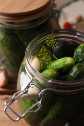 Jar with cucumbers, garlic and dill on wooden table, closeup. Pickling recipe