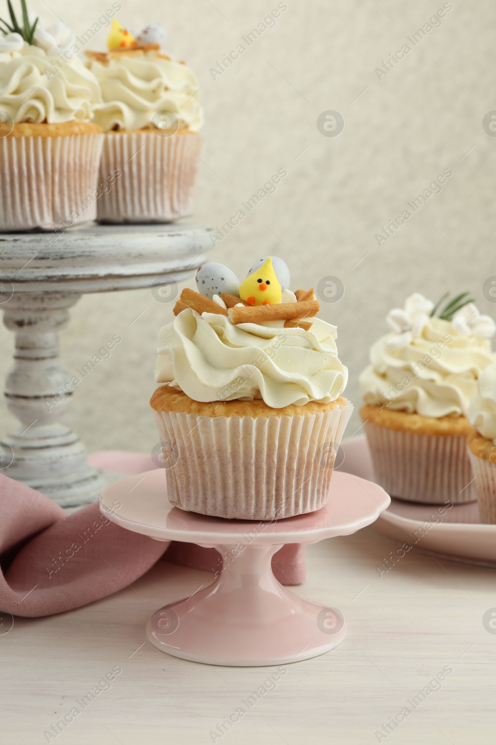 Photo of Tasty Easter cupcakes with vanilla cream on light wooden table