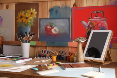 Photo of Artist's workplace with tablet, drawings, soft pastels and color pencils on table