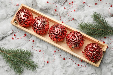 Beautiful Christmas baubles in box on white fur, above view