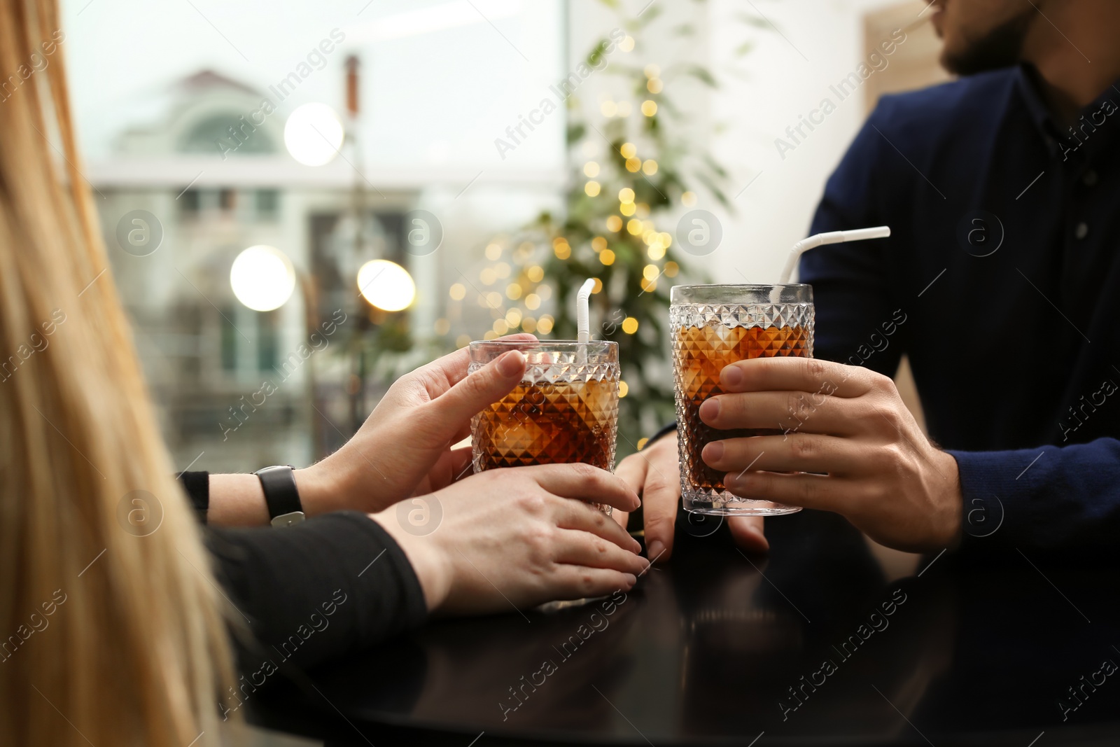 Photo of Couple with glasses of cold cola at table in cafe, closeup