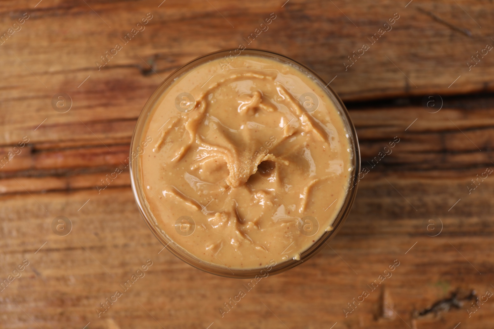 Photo of Delicious nut butter in bowl on wooden table, top view