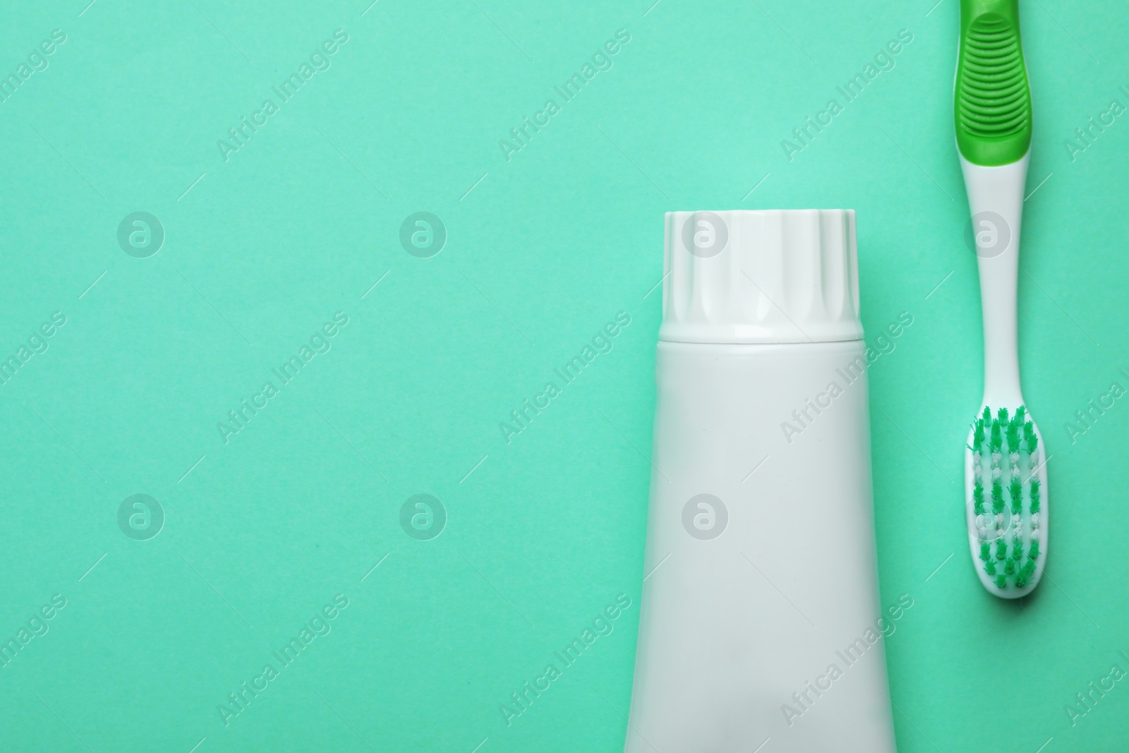 Photo of Blank tube of toothpaste and brush on color background, top view with space for text