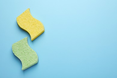 Photo of New sponges on light blue background, flat lay. Space for text