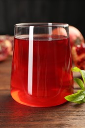 Photo of Tasty pomegranate juice in glass on wooden table, closeup