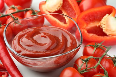 Bowl of tasty ketchup, tomatoes and peppers on white table, closeup