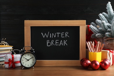 Photo of Chalkboard with phrase Winter Break, Christmas decor and stationery on wooden table. Holidays concept
