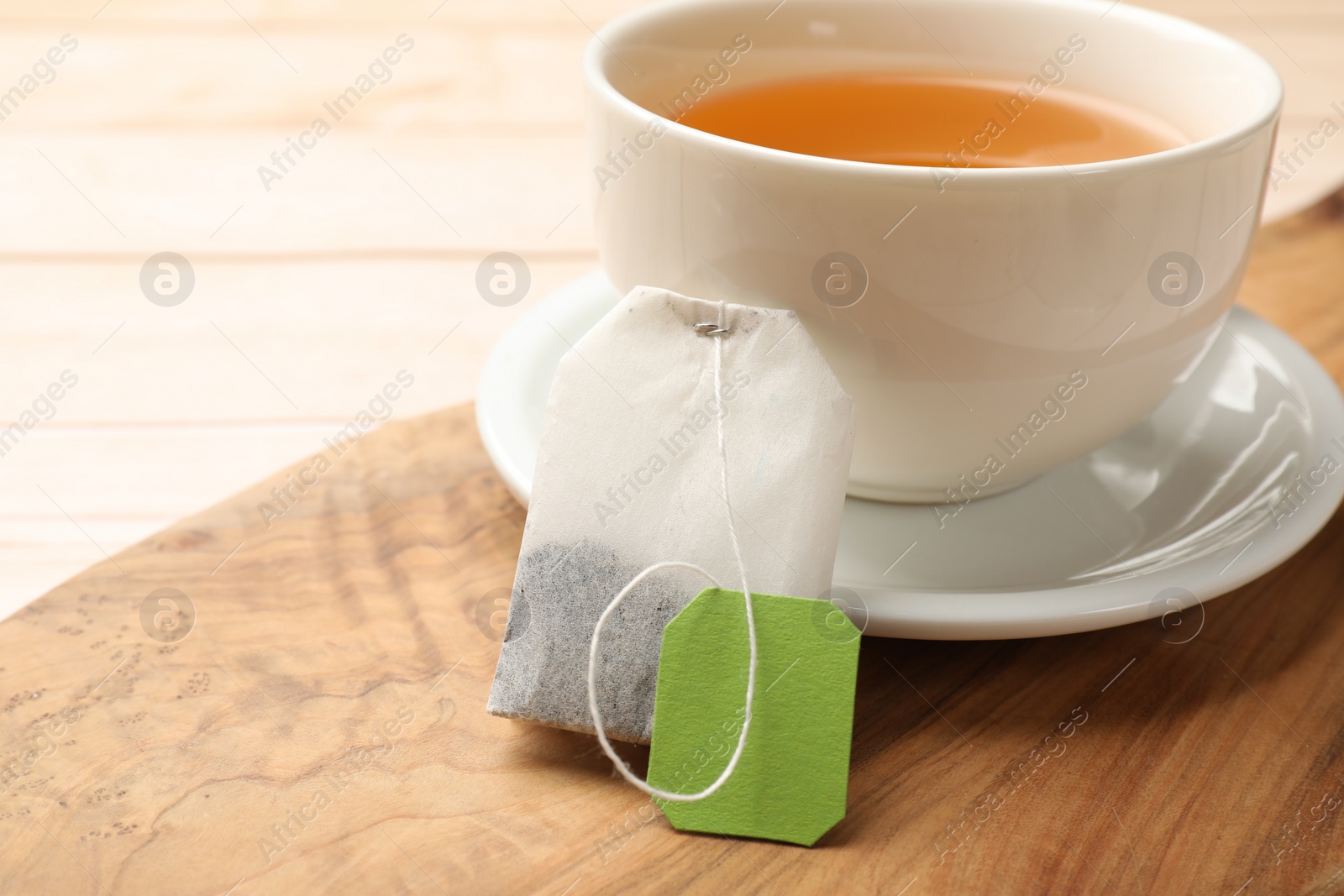 Photo of Tea bag and cup of hot beverage on light table, closeup. Space for text