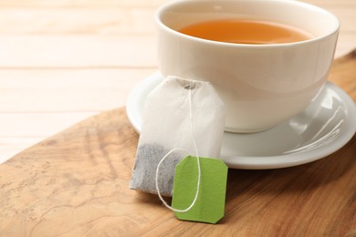 Photo of Tea bag and cup of hot beverage on light table, closeup. Space for text