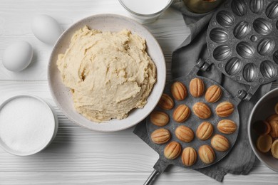 Photo of Delicious walnut shaped cookies and ingredients on white wooden table, flat lay