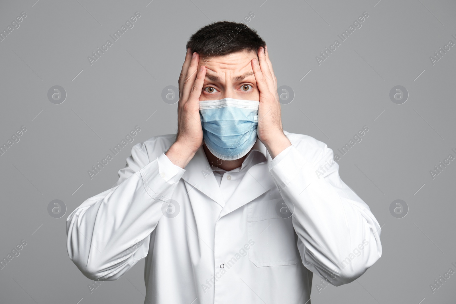 Photo of Portrait of doctor in protective mask feeling fear on grey background