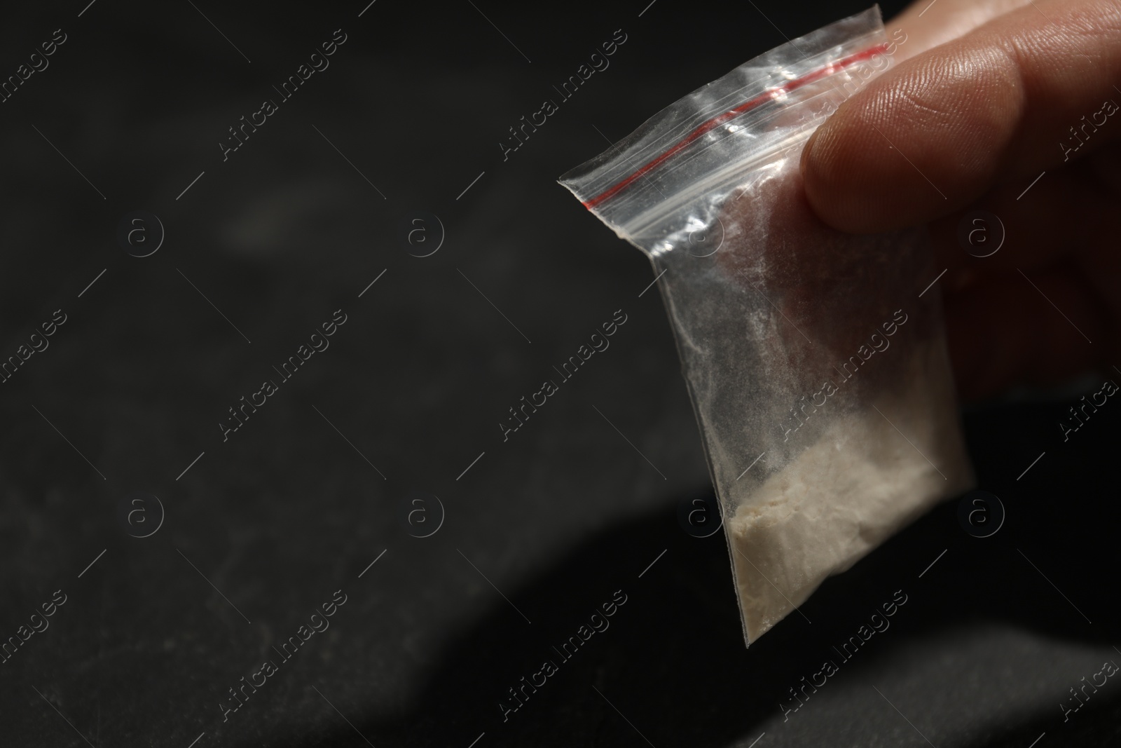 Photo of Addicted man with plastic bag of hard drug at grey table, closeup. Space for text