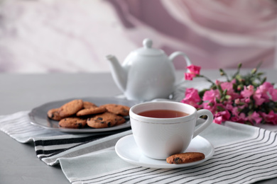 Photo of Cup of aromatic tea and tasty cookies on grey table