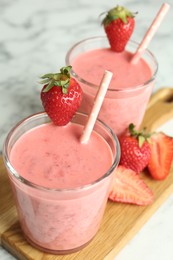 Photo of Tasty strawberry smoothies in glasses on wooden board, closeup