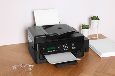 Photo of Modern printer with paper on wooden table indoors