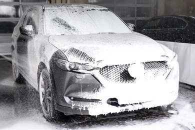 Cleaning automobile with high pressure water jet at car wash