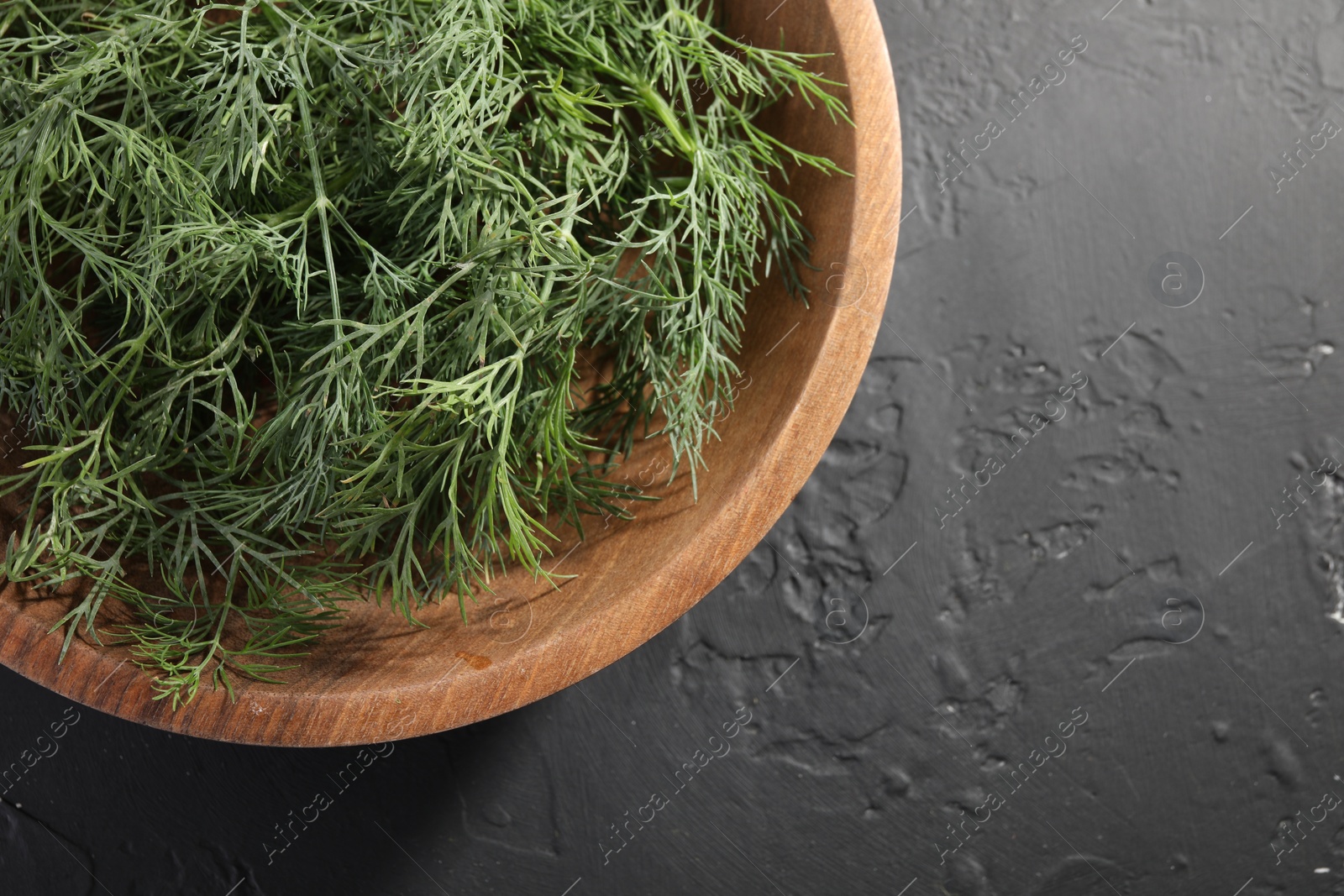 Photo of Bowl of fresh dill on grey textured table, top view. Space for text