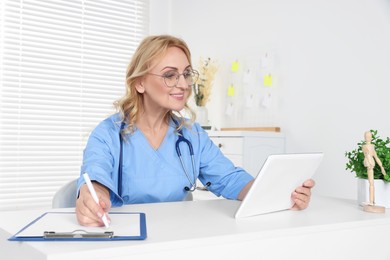 Doctor with glasses and tablet consulting patient in clinic. Online medicine concept