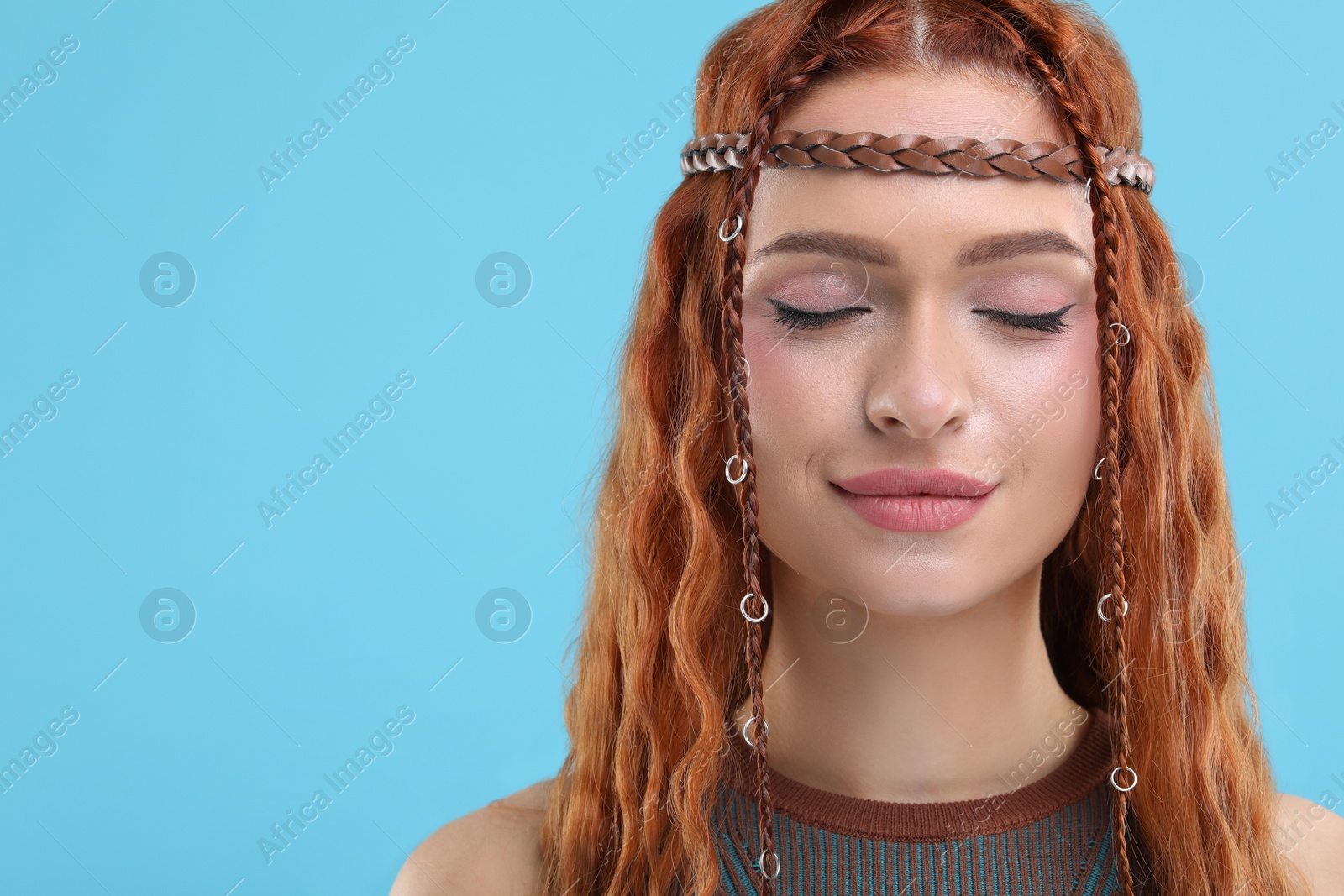 Photo of Beautiful young hippie woman on light blue background, closeup. Space for text