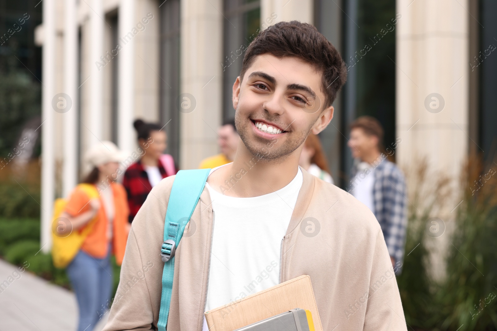 Photo of Happy young student with notebooks outdoors, selective focus