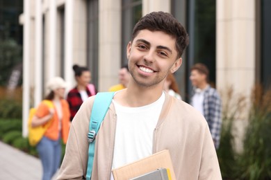Photo of Happy young student with notebooks outdoors, selective focus