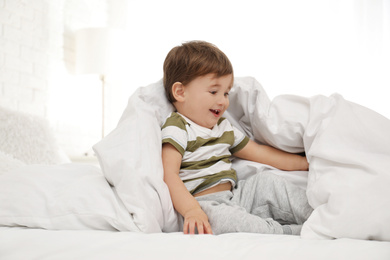 Cute little child playing under blanket in bed