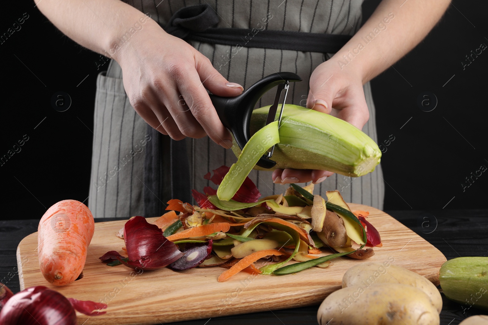 Photo of Woman peeling fresh zucchini at table, closeup