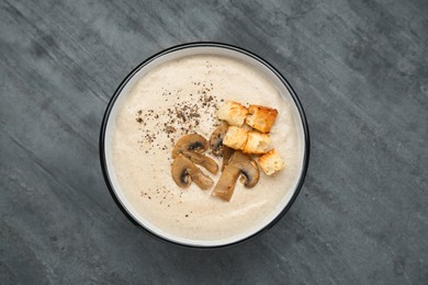 Photo of Delicious cream soup with mushrooms and croutons on black table, top view
