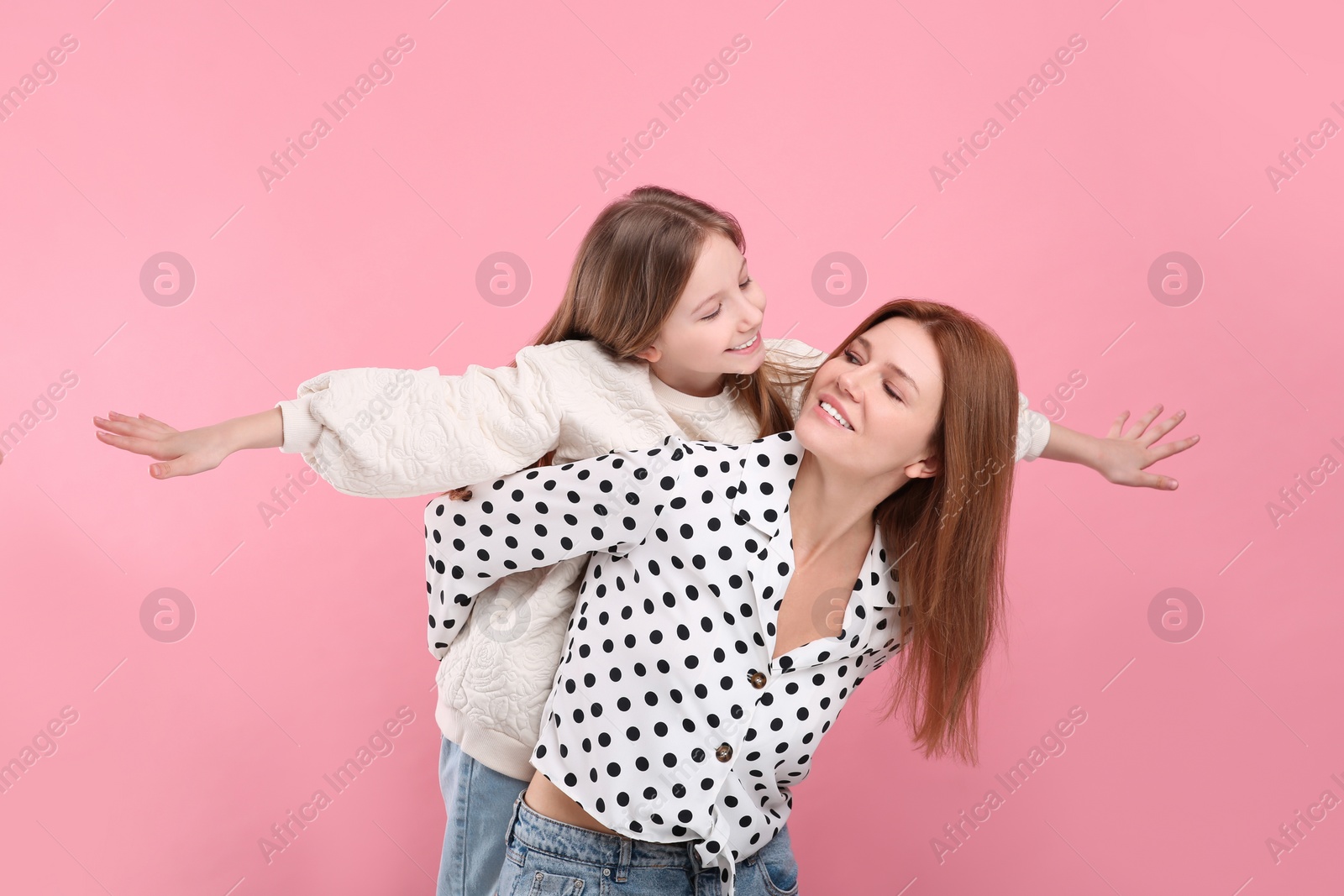 Photo of Happy mother with her cute daughter on pink background