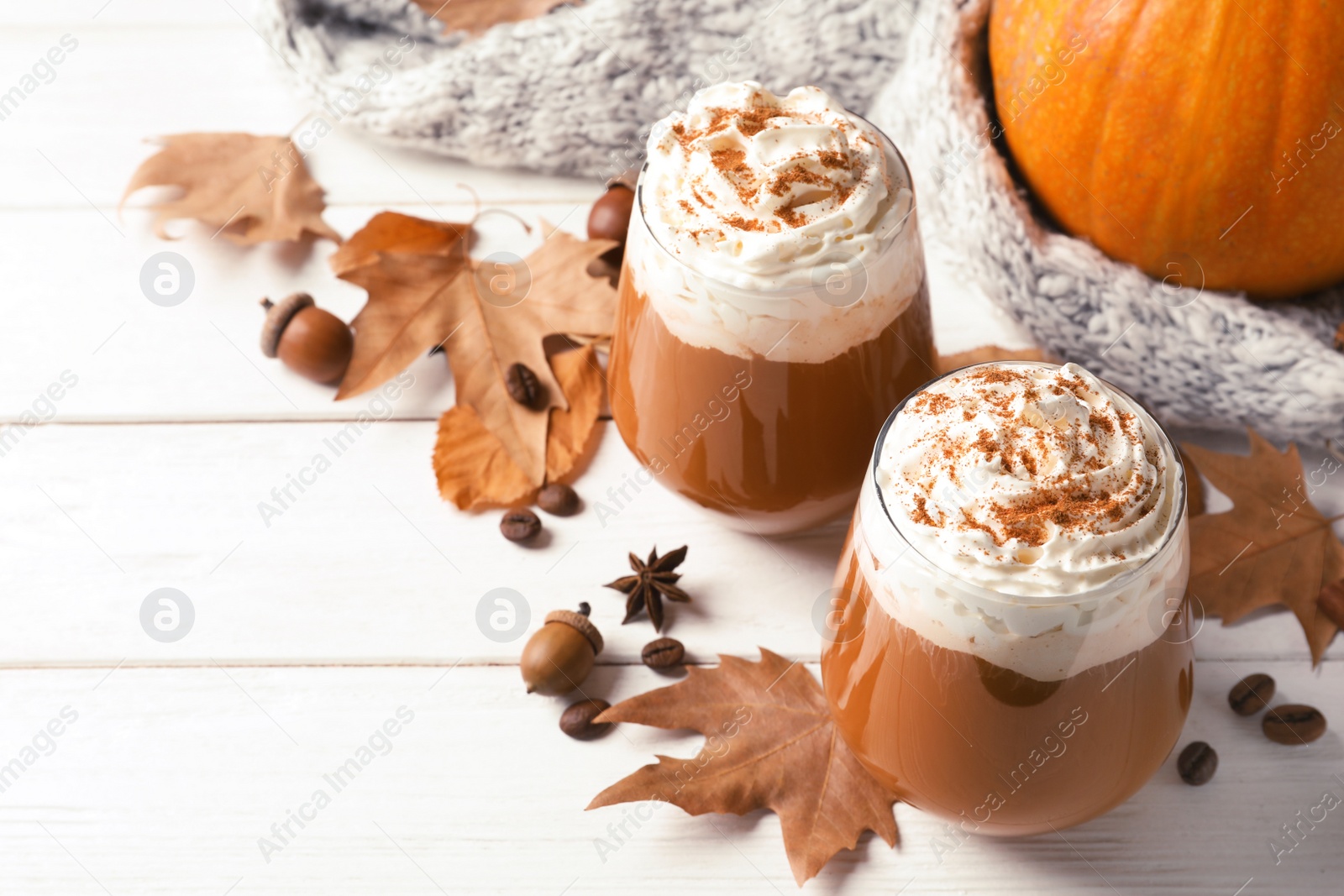 Photo of Glasses with tasty pumpkin spice latte and space for text on wooden table