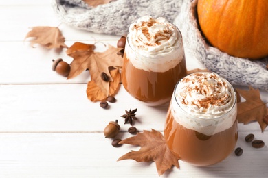 Photo of Glasses with tasty pumpkin spice latte and space for text on wooden table
