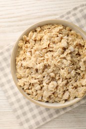 Photo of Tasty boiled oatmeal in bowl on light wooden table, top view